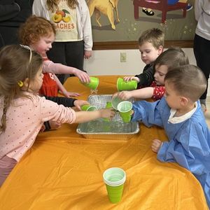 preschoolers scoop water out of bin