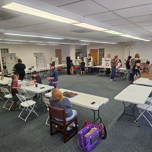 photo of library's community room where tables are set up with science fair projects and people are walking around looking at them
