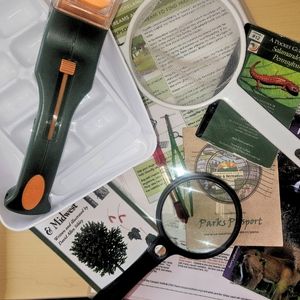 all of the items contained with one of the Westmoreland Nature Backpacks are shown: small butterfly net, bug magnifying glass, tweezers, maps, field guides and other supplies for an educational nature hike