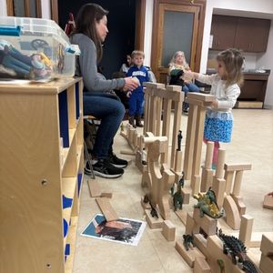 preschool aged child builds a large structure out of wooden building blocks